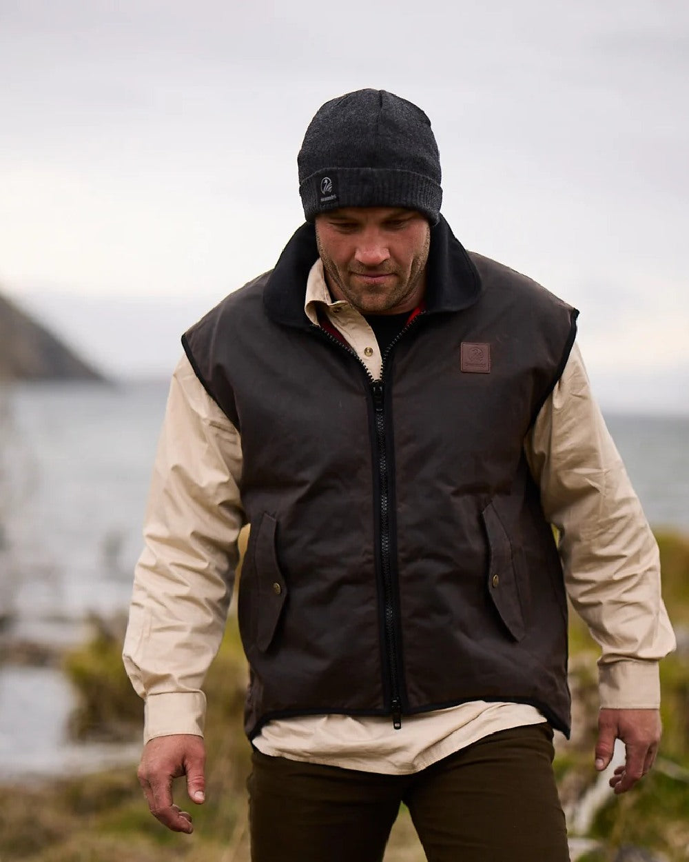 Brown Coloured Swanndri Mens Foxton Oilskin Vest with Wool Lining on blurry background 