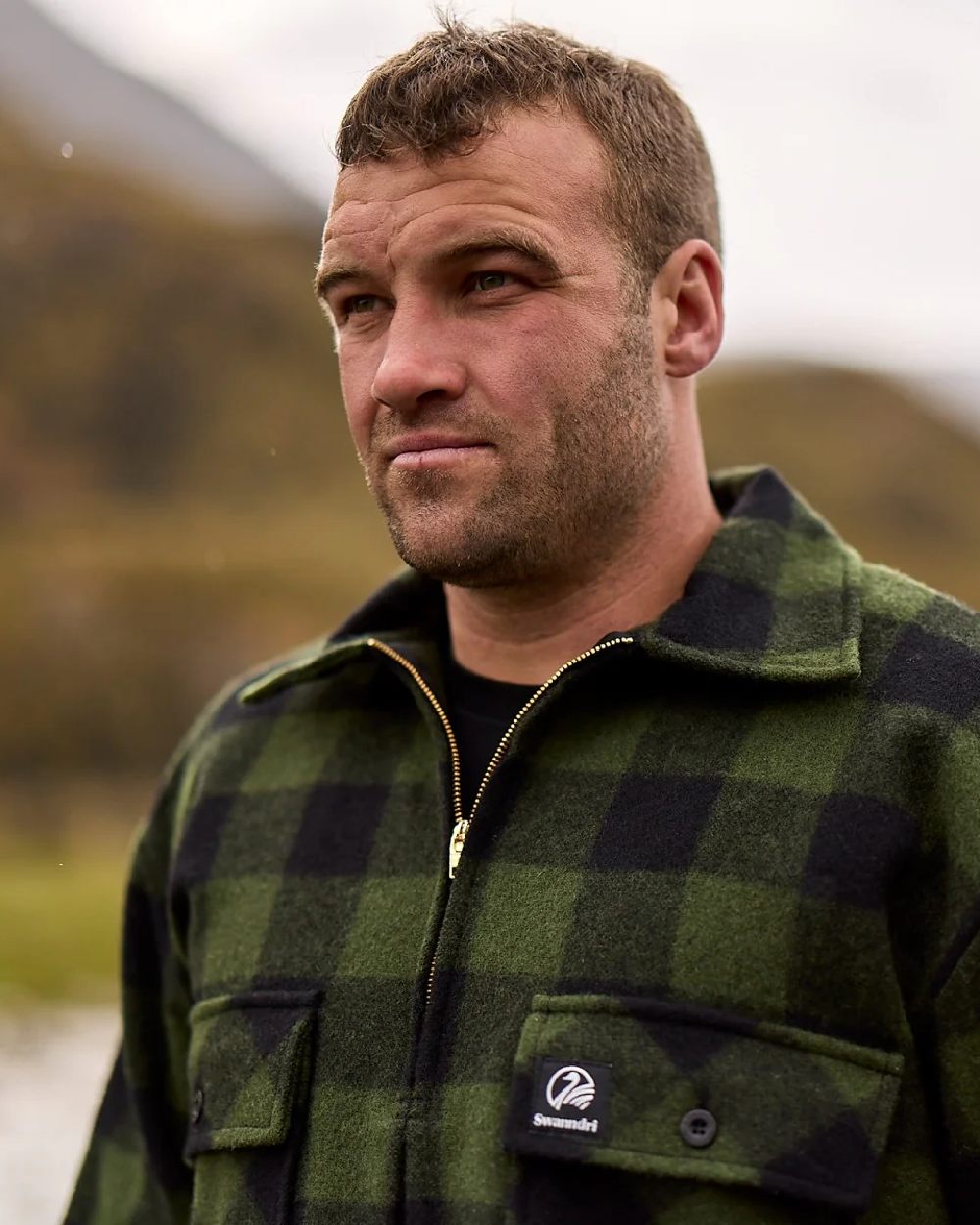 Olive Black Check Coloured Swanndri Mens Ranger Wool Zip Front Bushshirt on blurry background 