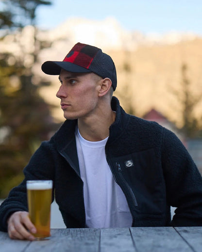 Red Black Check Coloured Swanndri Swanni Trucker Cap on blurry background 