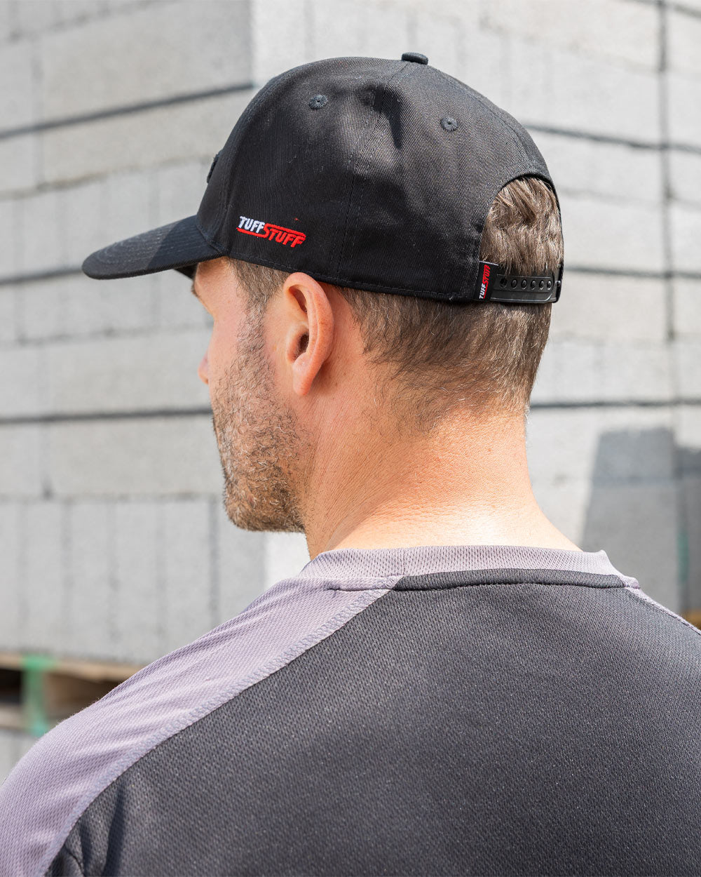 Black coloured TuffStuff Baseball Cap on Model with Construction background 