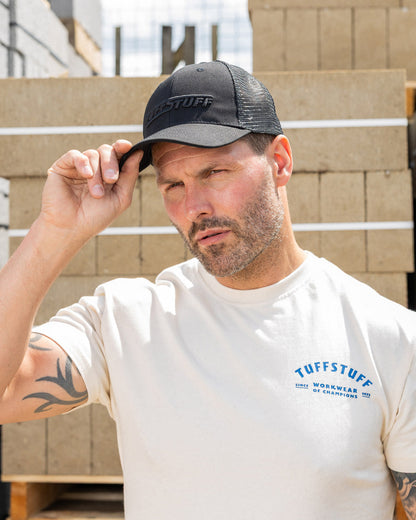 Black coloured TuffStuff Trucker Cap on Model with construction background 