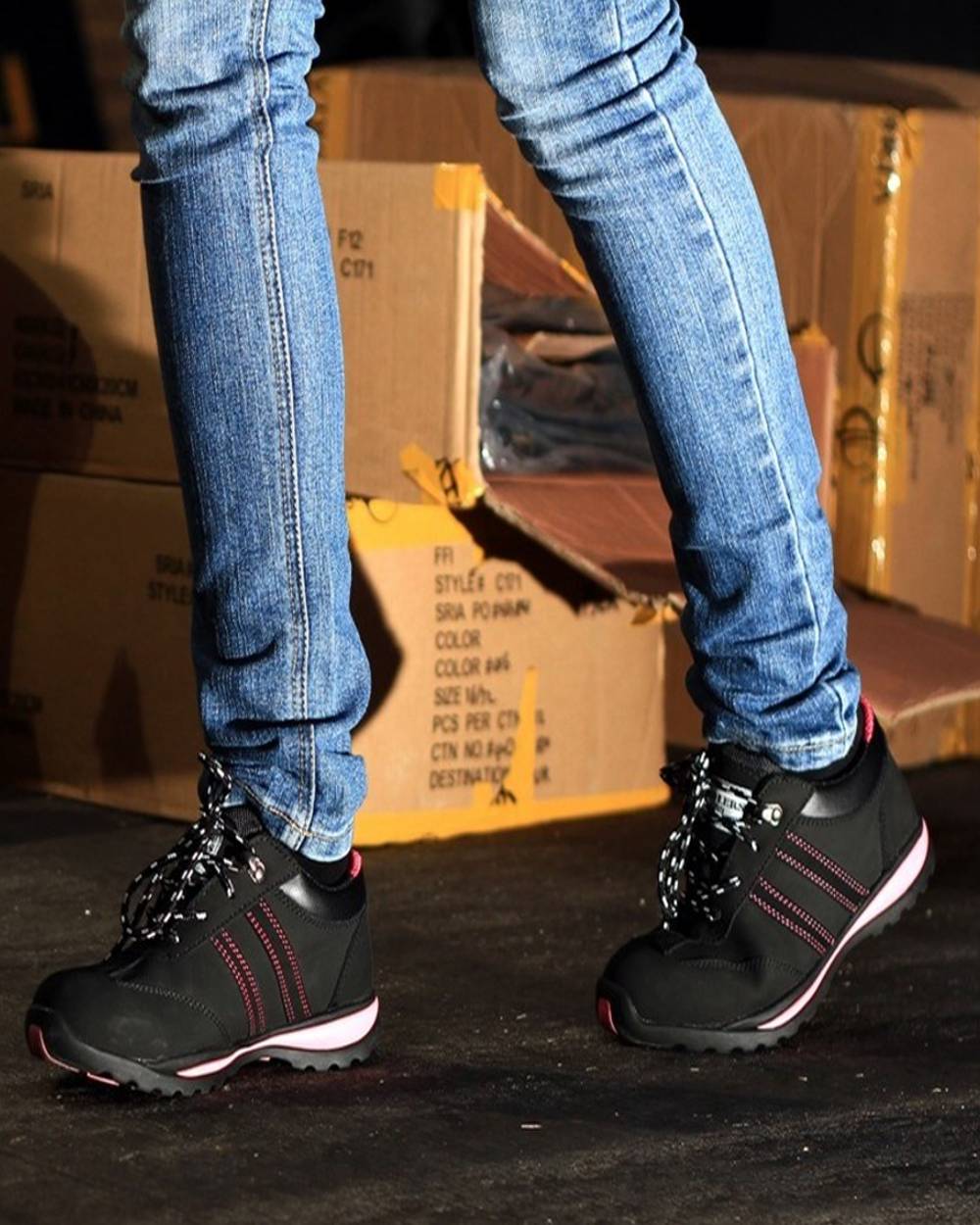 Black Pink Coloured Amblers Safety FS47 Safety Trainer on a warehouse background