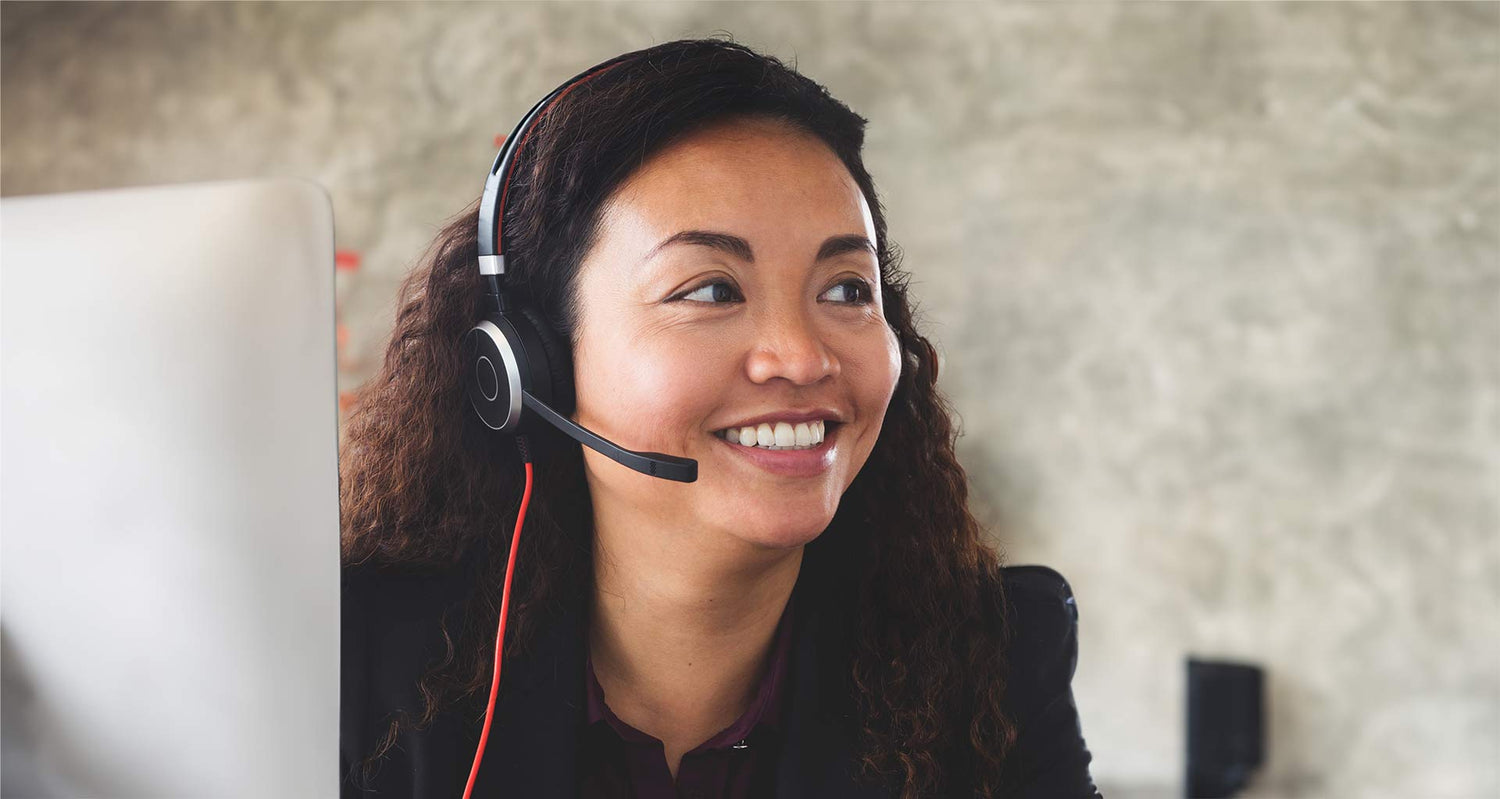 Customer Service lady with headset on taking a customers call in a friendly smiling manner.