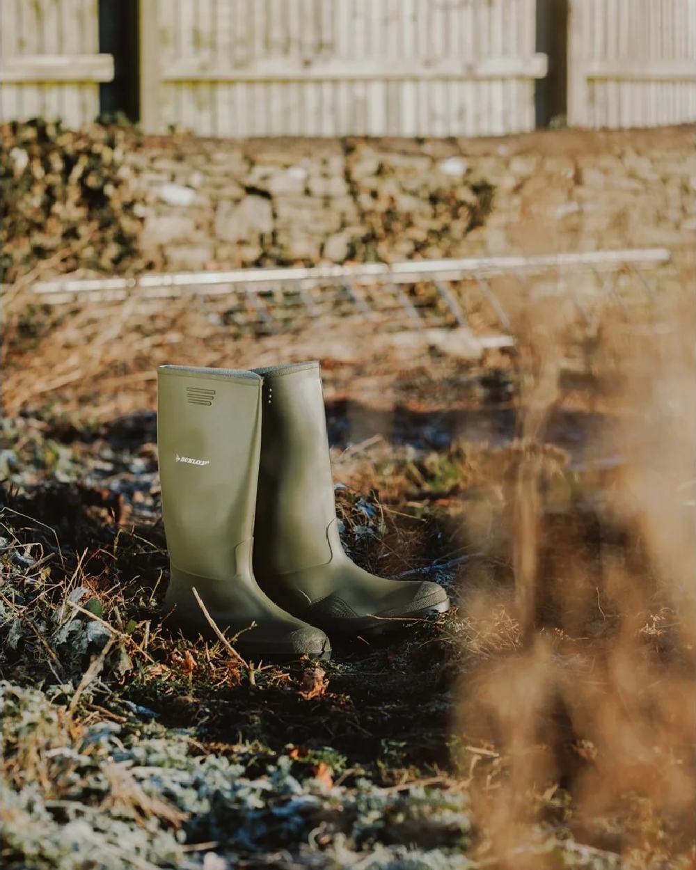 Green coloured Dunlop Pricemastor Wellingtons on blurry background 