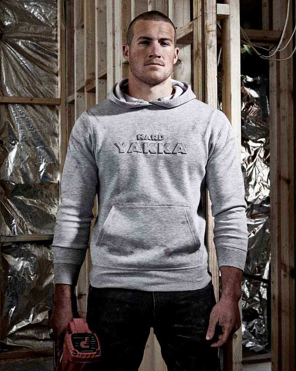 Light Grey Coloured Hard Yakka Mens Embossed Pullover Hoodie on Wooden Studs Background
