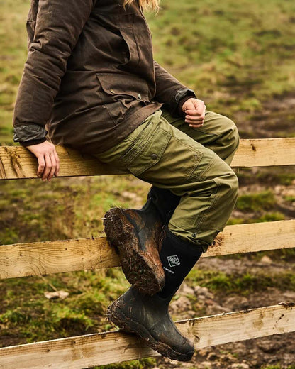 Black Coloured Muck Boots Derwent II Wellingtons On A Forest Background 