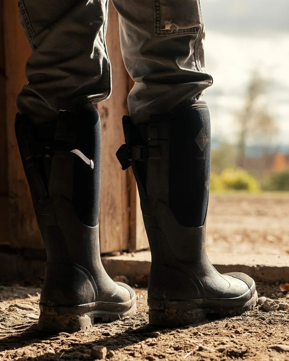 Black Coloured Muck Boots Womens Chore Adjustable Tall Wellingtons On A Field Background