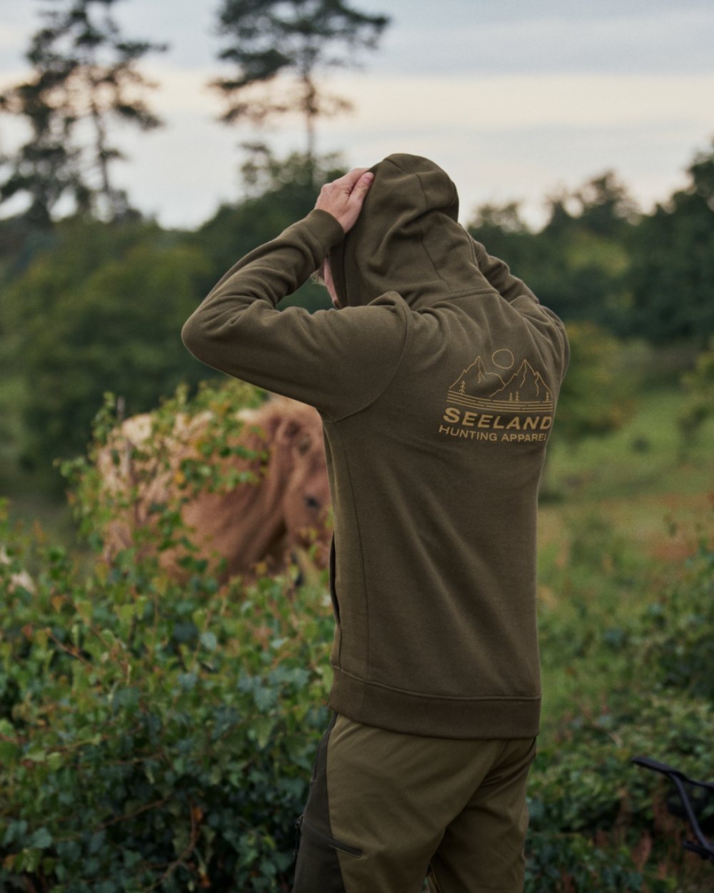 Grizzly Brown Coloured Seeland Kelvin Hoodie On A Forest Background