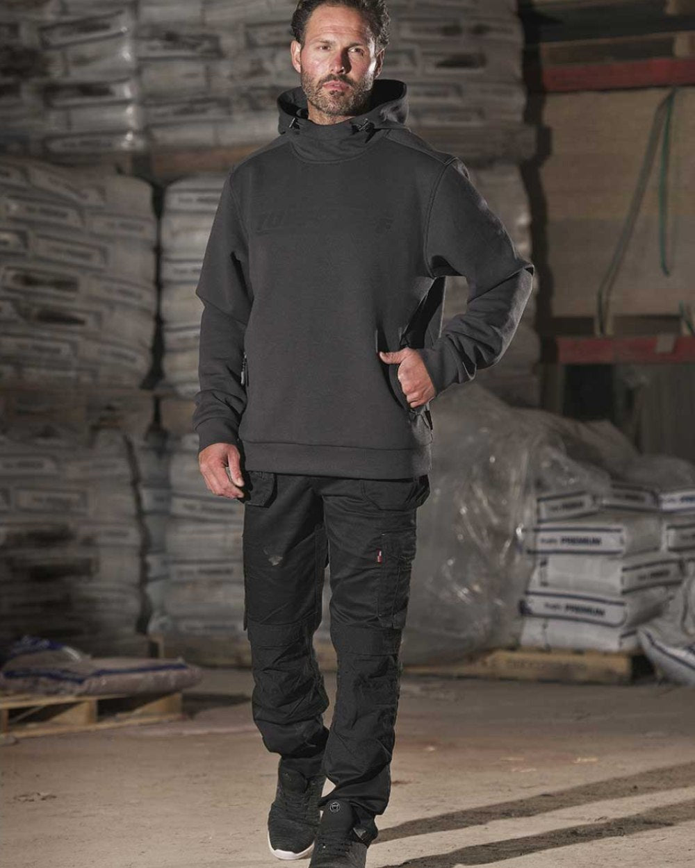 Black Coloured TuffStuff Extreme Work Trousers On A Warehouse Background 