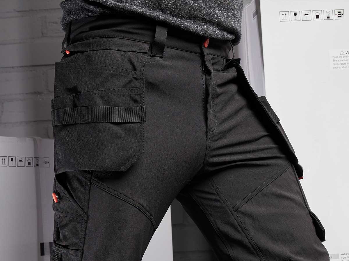 Work Trousers. A pair of black work trousers with lots of pockets, close up of waist area.