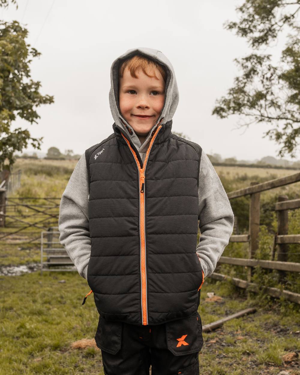 Black Coloured Xpert Childrens Pro Rip-Stop Panelled Bodywarmer on Outdoor Background

