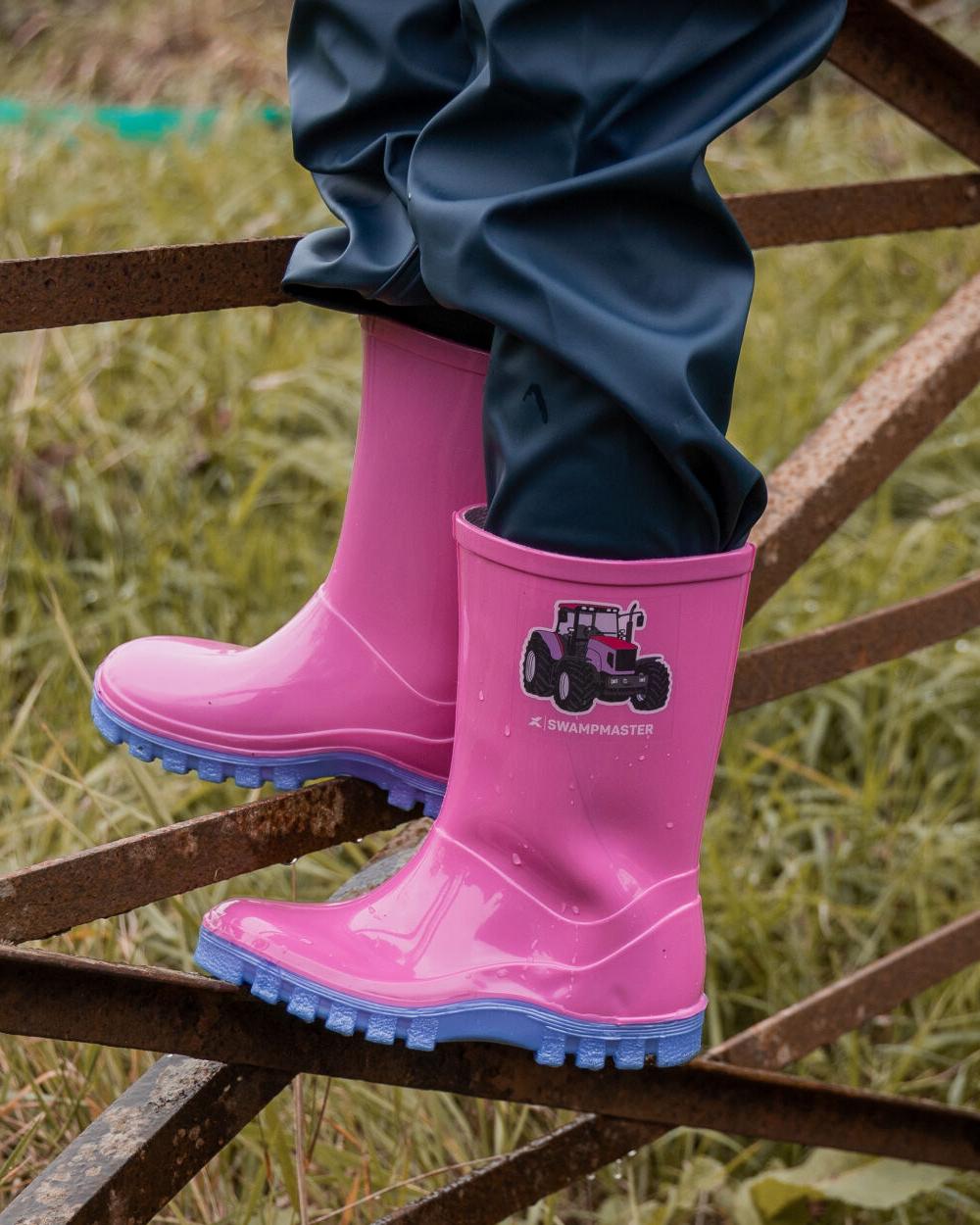 Pink Lilac Coloured Xpert Childrens Swampmaster Tractor Wellingtons on Outddor Background
